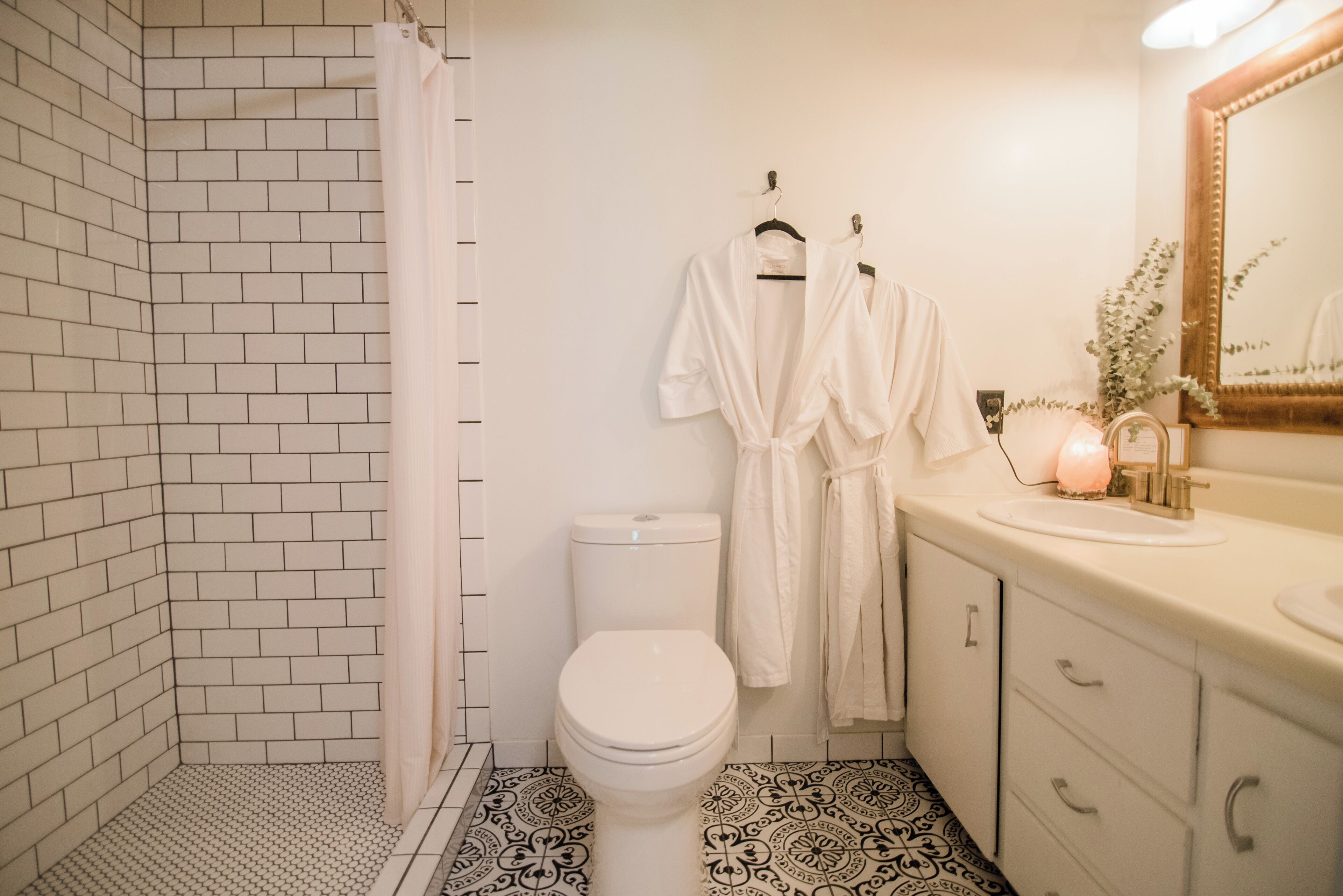 A bathroom with a white toilet, a shower with a white curtain, and a sink with a mirror.