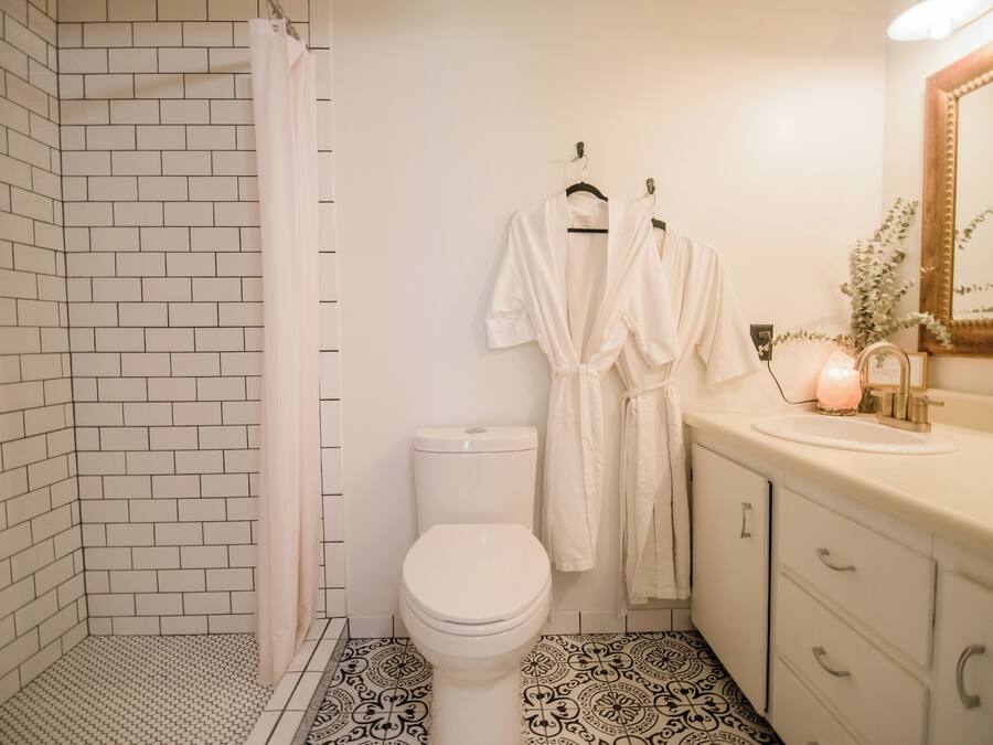 A bathroom with a white toilet, a shower with a white curtain, and a sink with a mirror.