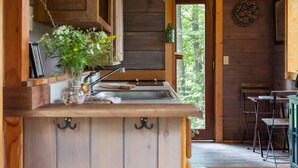 Una cocina rústica con armarios de madera, un lavamanos y un comedor con sillas de metal.