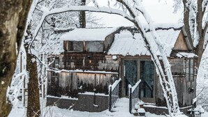 Una cabaña de madera con techo nevado y un porche de madera.