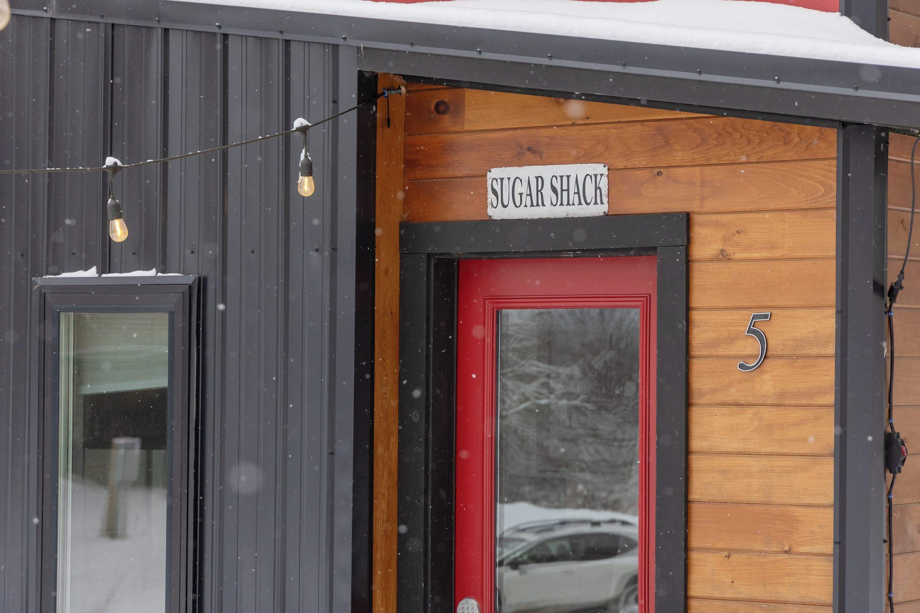Un edificio con una puerta roja y un letrero que dice 'SUGAR SHACK'.