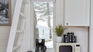Una cocina compacta con microondas, cafetera y un refrigerador pequeño.