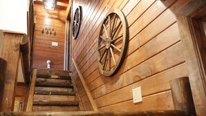 A wooden staircase with wooden walls and two large wooden wheels mounted on the wall.