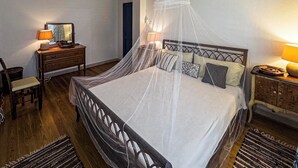 A bedroom with a bed, wooden headboard, bedside tables, a nightstand, a chair, a desk, a lamp, a ceiling fan, and a window. - "Beyond" a paradise in Barbados (Cattlewash)