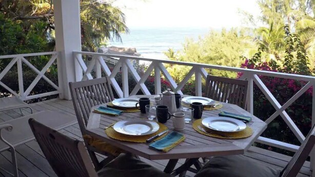 A wooden deck with a table set for four, overlooking a scenic view. - "Beyond" a paradise in Barbados (Cattlewash)