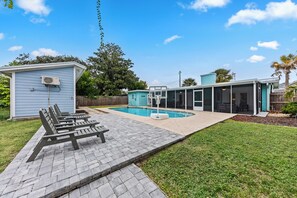 A backyard with a swimming pool, a small shed, and a covered patio area.