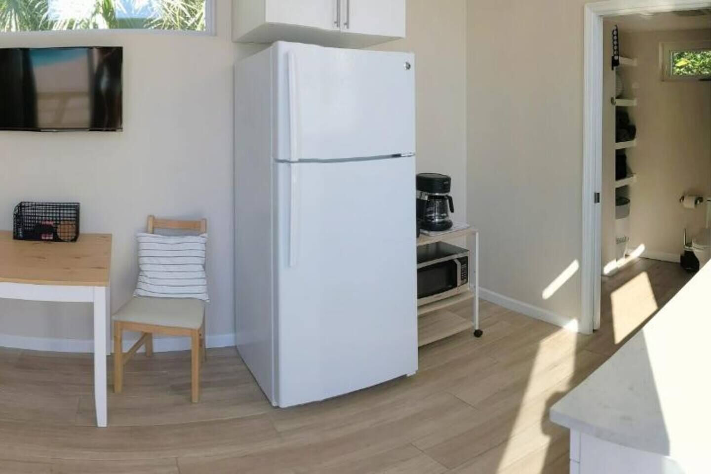 Una cuina compacta amb un frigorífic blanc, una taula de fusta i una cadira.