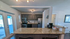 A modern kitchen with granite countertops, dark wood cabinets, and a central island with bar stools.