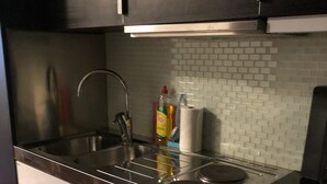 Eine Küche mit Edelstahlgeräten, einer weißen Fliesenrückwand und einer schwarzen Arbeitsplatte.