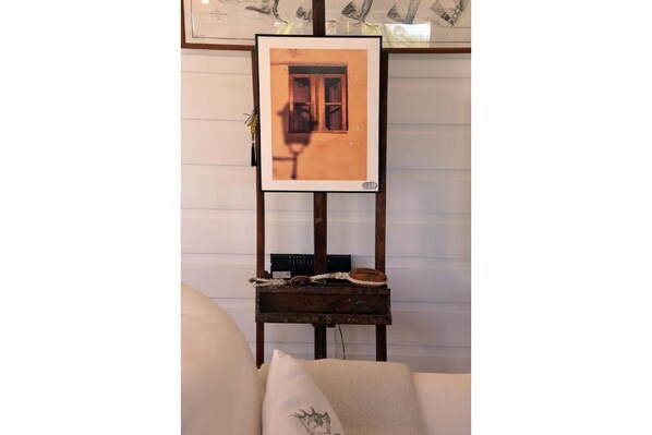 A framed photograph on a wooden easel in a room with a white wall and a white couch.