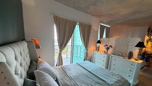 Un dormitorio con cama, cómoda, espejo y ventana con cortinas.