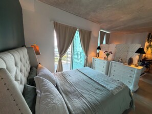 A bedroom with a bed, a dresser, a mirror, and a window with curtains.