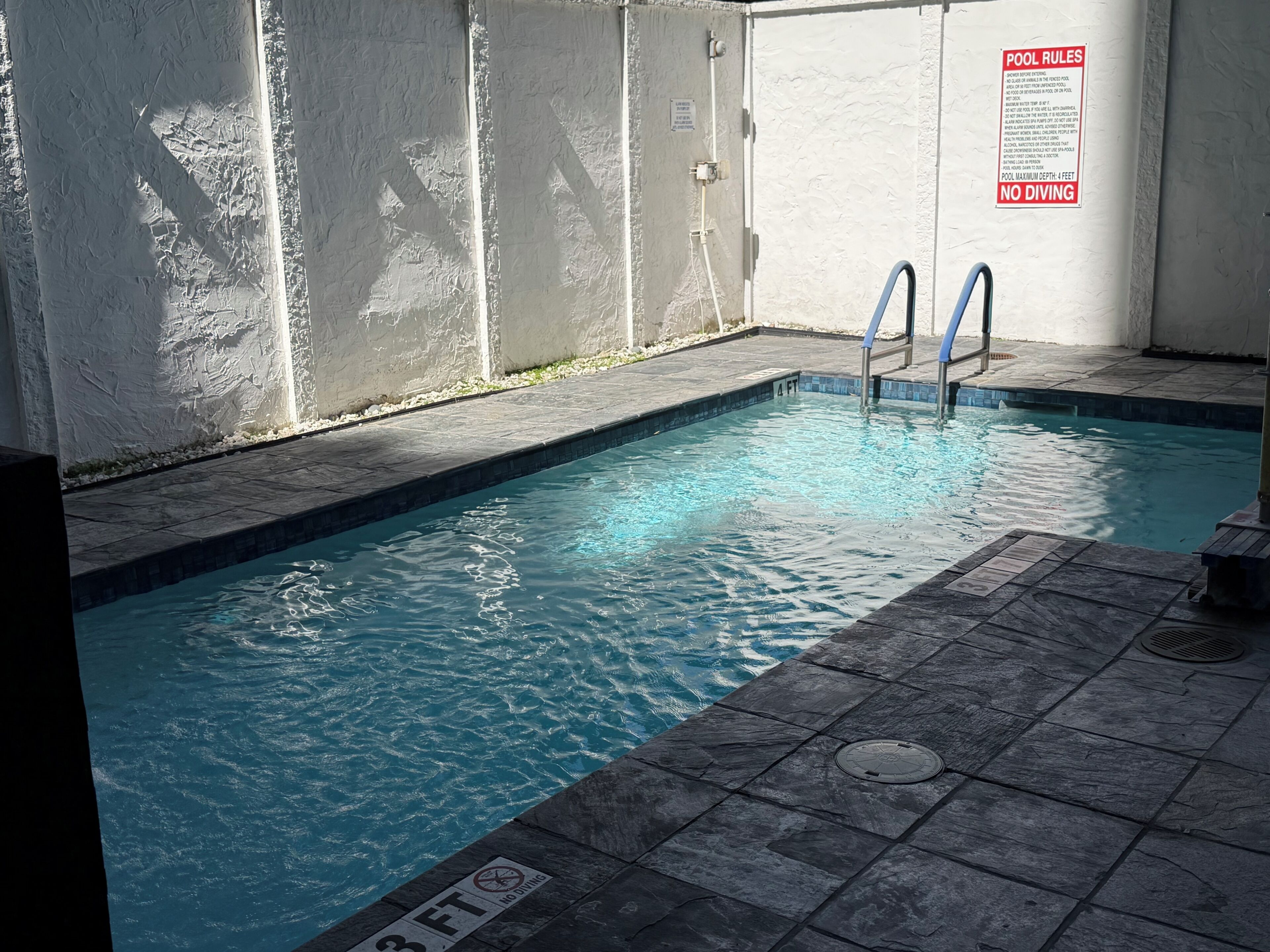 A swimming pool with a no diving sign, a pool rules sign, and a depth marker of 8 feet.