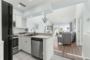 A modern kitchen with a dishwasher, stove, and microwave. There is a dining area with a table and chairs.