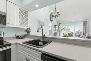 A modern kitchen with a black sink, white cabinets, and a chandelier.