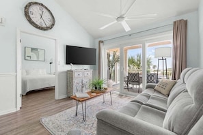 A living room with a sofa, a coffee table, a television, and a ceiling fan.