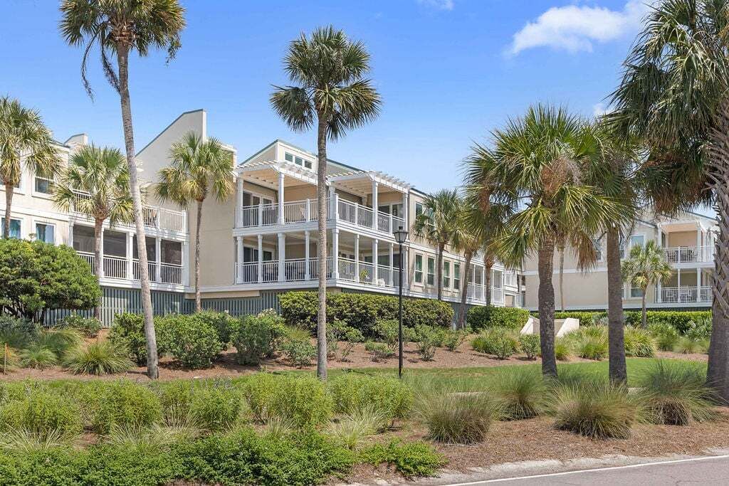 A multi-story hotel with balconies, surrounded by palm trees and landscaped gardens.