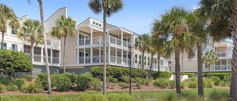 A multi-story hotel with balconies, surrounded by palm trees and landscaped gardens.