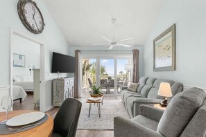 A modern living room with a sofa, a television, and a dining area with a table and chairs.