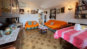 Ein gemütliches Wohnzimmer mit zwei orangefarbenen Sofas, einem Holzschrank, einem Fernseher und einem Bücherregal.
