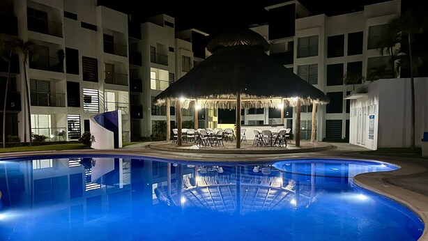 A swimming pool with a thatched-roof gazebo and lounge chairs. - 5 minutes from the beach and pool (manzanillo)