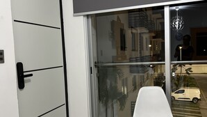 A modern room with a sliding glass door leading to a balcony, a white chair, and a door with a black handle. - 5 minutes from the beach and pool (manzanillo)