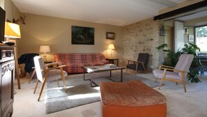 A living room with a sofa, two armchairs, a coffee table, and a fireplace. - Le Potager - Martigny-le-comte (MARTIGNY-LE-COMTE)