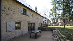 A stone building with a patio area, a bench, and a stone wall. - Le Potager - Martigny-le-comte (MARTIGNY-LE-COMTE)
