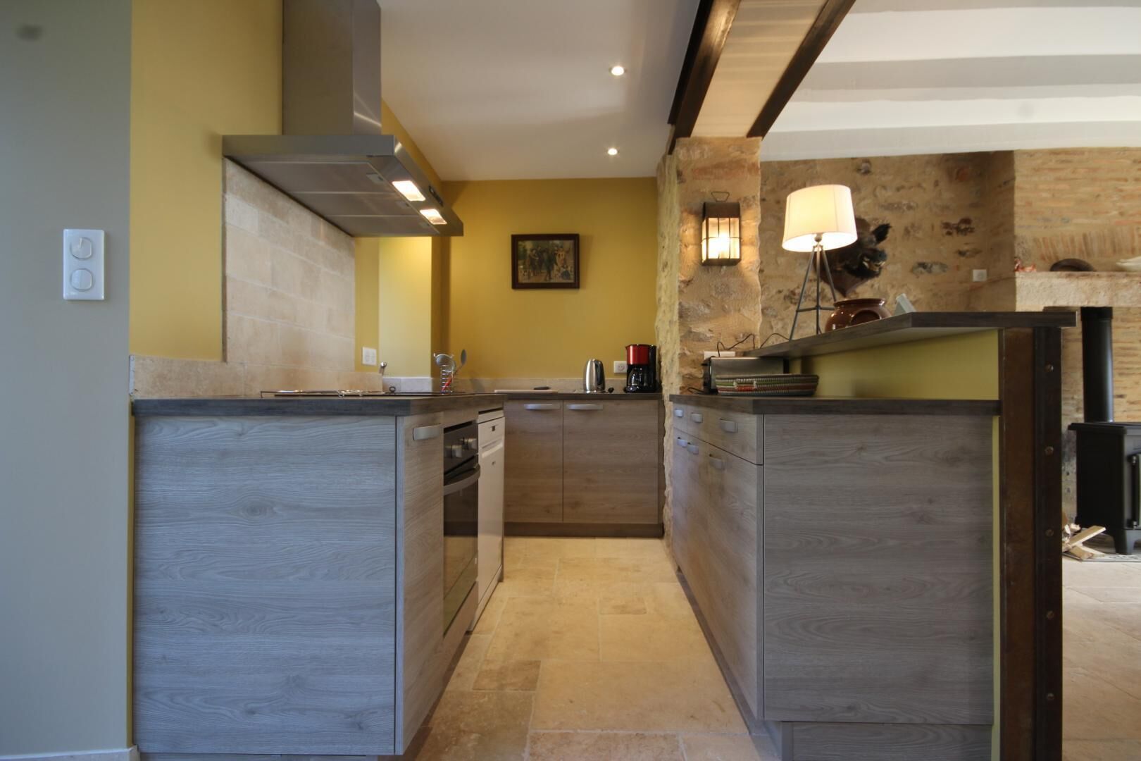 Eine moderne Küche mit einer zentralen Kochinsel, Holzschränken und einer Wand mit Natursteinverkleidung.