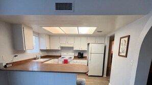 A modern kitchen with white cabinets, a wooden countertop, and a central island. - Casa Moldavia (Bullhead City)
