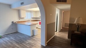 An open-plan living area with a kitchen, wooden flooring, and a hallway leading to another room. - Casa Moldavia (Bullhead City)