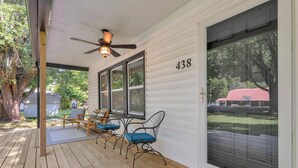 A covered porch with a ceiling fan, a wooden table with chairs, and a sliding glass door with the number 438.