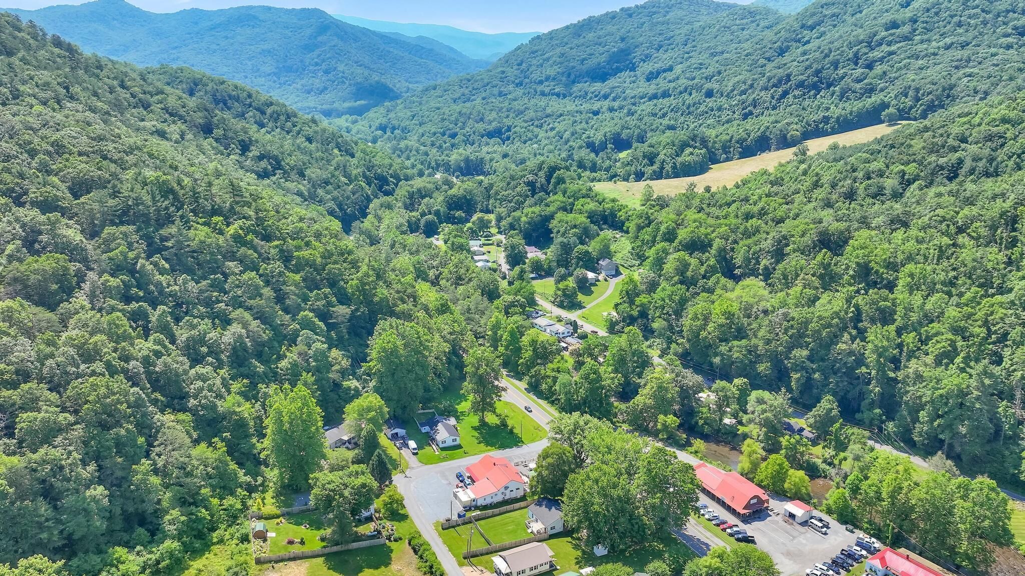 Vue aérienne d’un quartier résidentiel avec des maisons, des routes et des collines boisées environnantes.