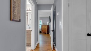 A hallway with a wooden floor, a white door, and a dresser in the background.