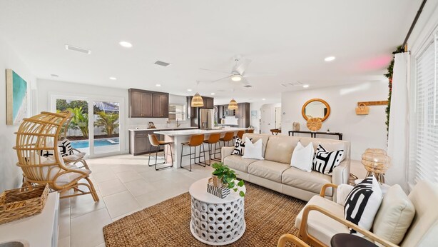 Una sala de estar moderna con un sofá, sillones, una mesa de centro y un comedor, con una cocina al fondo.