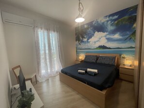 A bedroom with a bed, a nightstand, a lamp, a plant, and a window with curtains. - Luxury vacation home with a reserved parking space (Giardini Naxos)