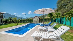 A swimming pool with white lounge chairs and a stone building in the background.