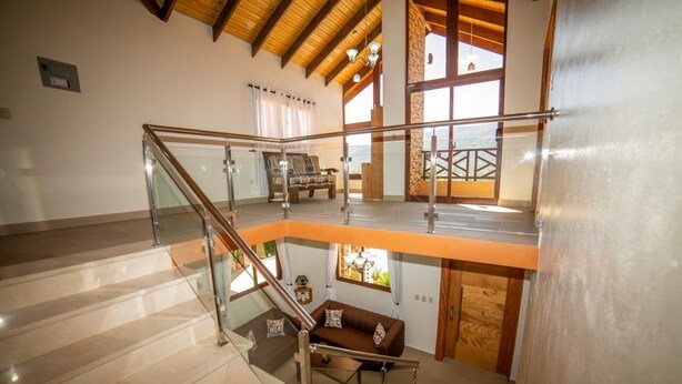 A spacious interior with a glass staircase leading to a second-floor balcony.