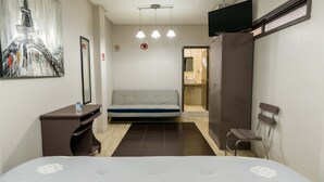 A hotel room with a bed, a desk, a chair, a TV, and a shower area. - Hotel Boutique 5ta avenida (Córdoba)