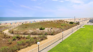 A beach with a fenced area, a grassy lawn, and a pathway.