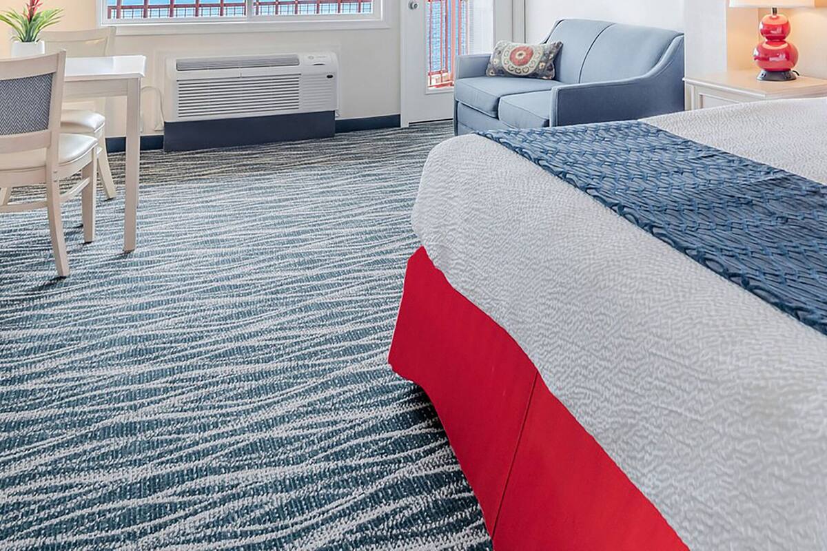 A hotel room with a large bed, a desk, a chair, and a sofa.