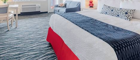 Una habitación de hotel con una cama grande, un escritorio, una silla y un sofá.
