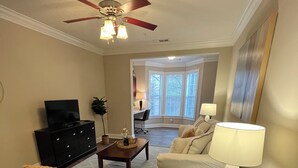 Ein Wohnzimmer mit Deckenventilator, Fernseher, Couchtisch, Sofa und Lampe.