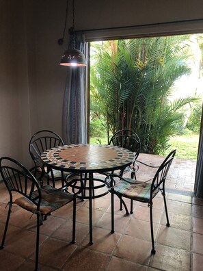 A round table with a mosaic top, surrounded by four chairs with cushioned seats and backs.