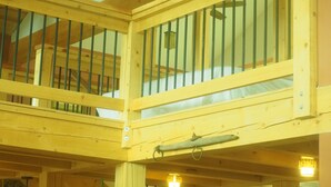 A wooden balcony with a bed and a hanging light fixture.