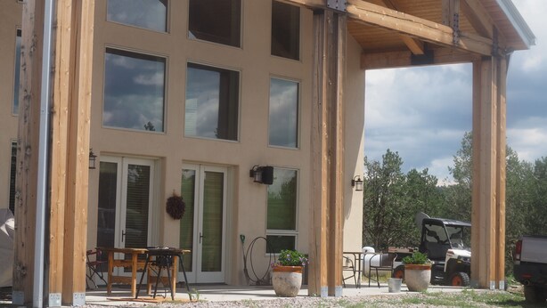 A building with a covered patio area, large windows, and a door with a glass door.