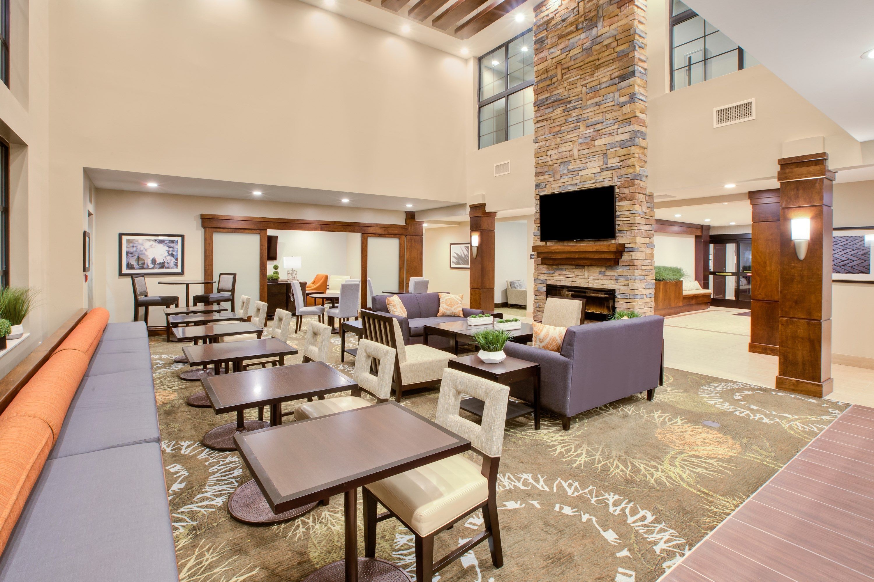 A spacious indoor area with multiple seating arrangements including sofas and tables, a fireplace, and a television mounted on the wall.