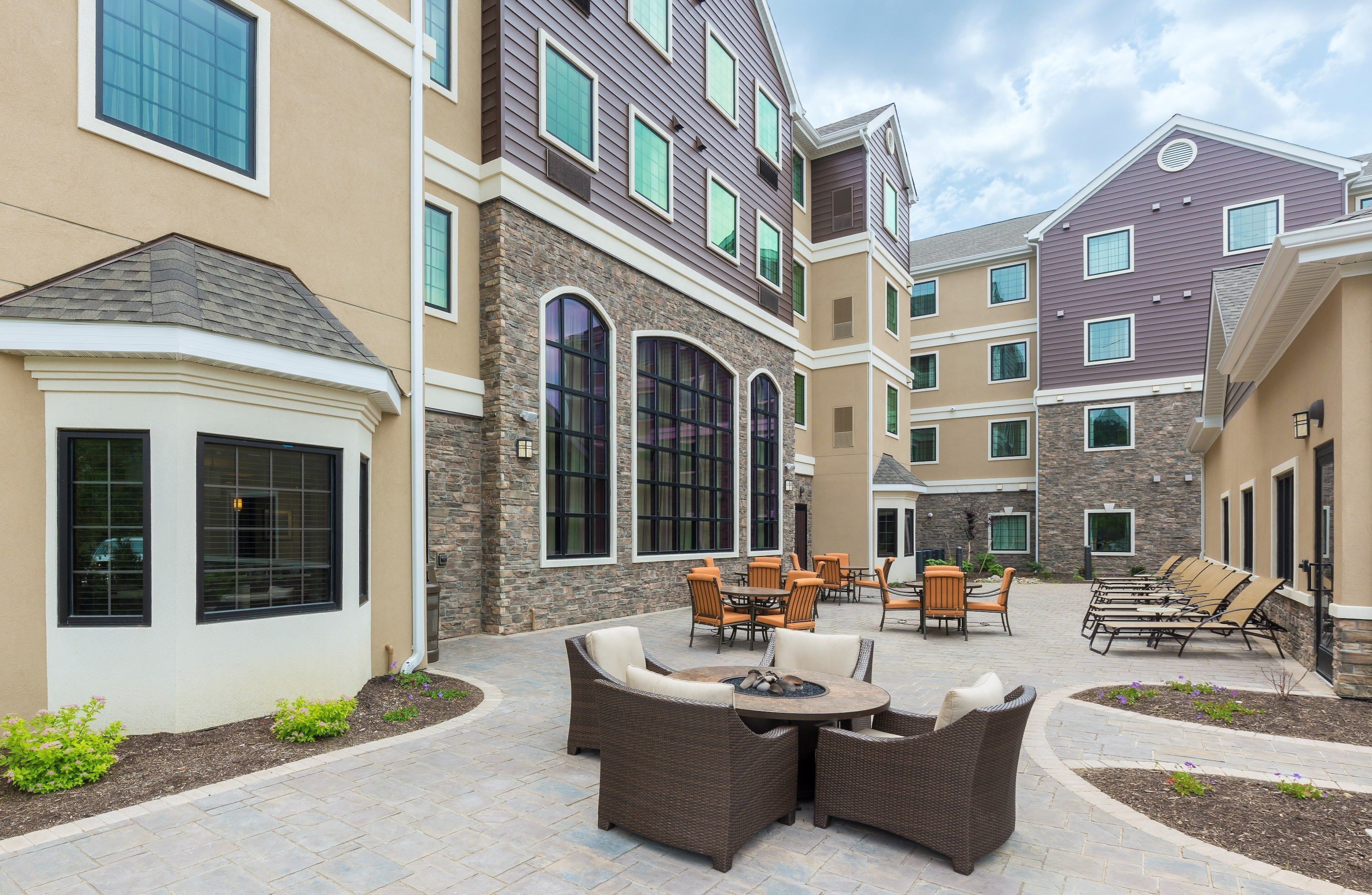 A courtyard with outdoor seating, stone walls, and large windows.