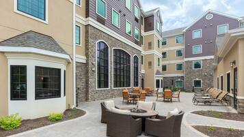A courtyard with outdoor seating, stone walls, and large windows.