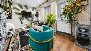A modern living room with a teal armchair, a flat-screen TV, and a large potted plant. - Luxury 1bed Studio Apt-city Centre-wifi-parking (Maidstone)